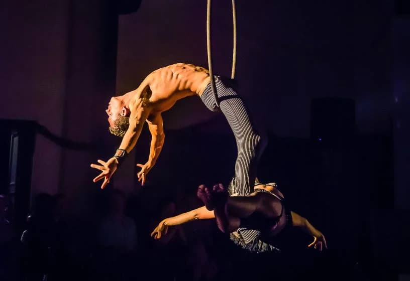 Aerial duo performing on hoops under dramatic lighting