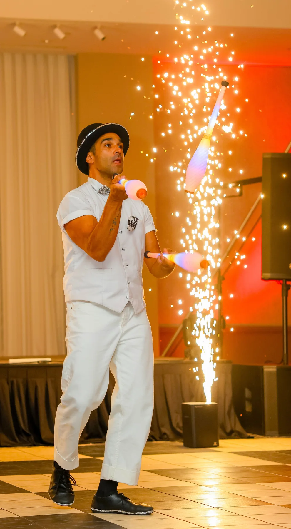 Juggler performing indoors with spark effects behind him