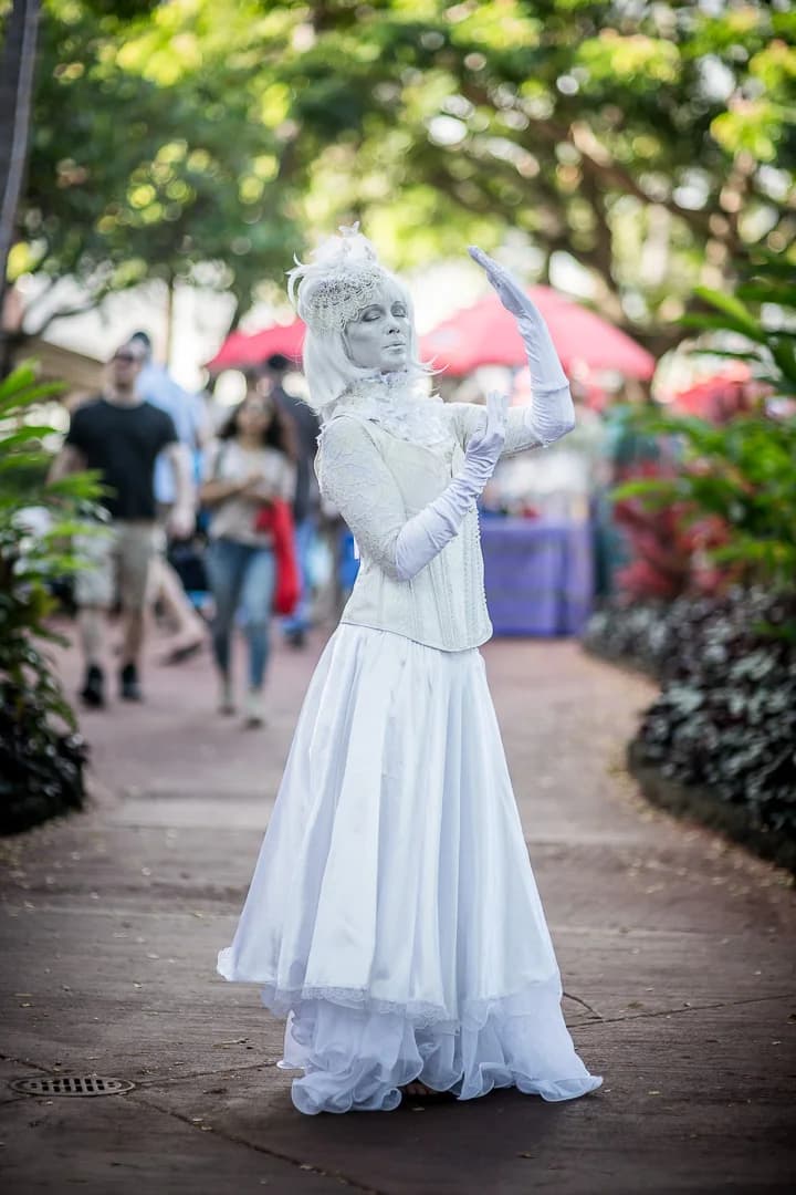 Living statue performer in white costume greeting guests