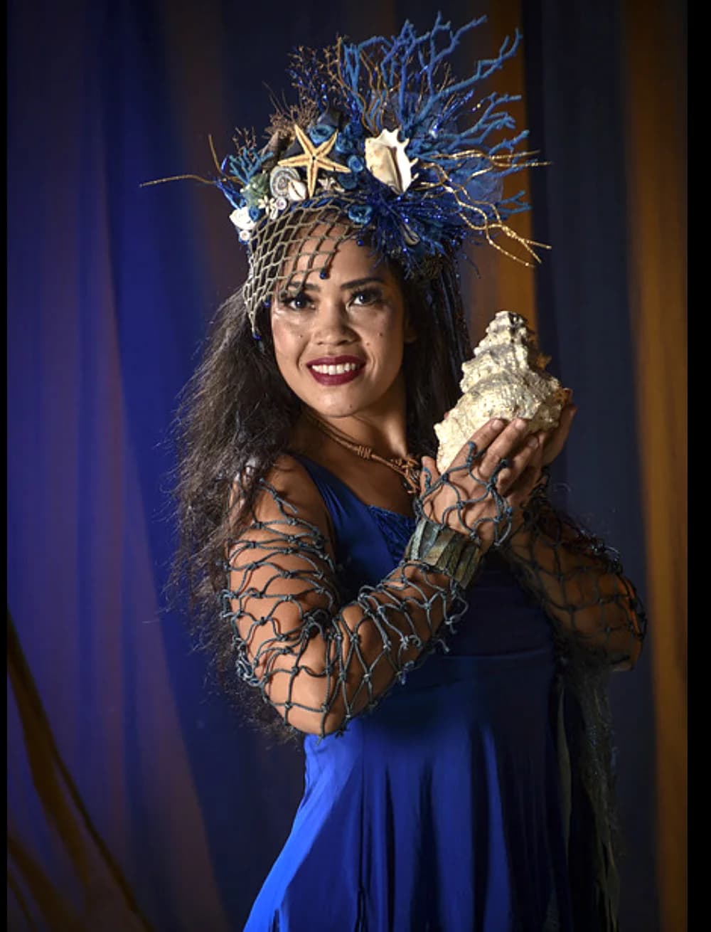 Ocean goddess performer holding a conch shell in blue costume