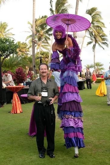 Purple stilt walker posing with a corporate guest