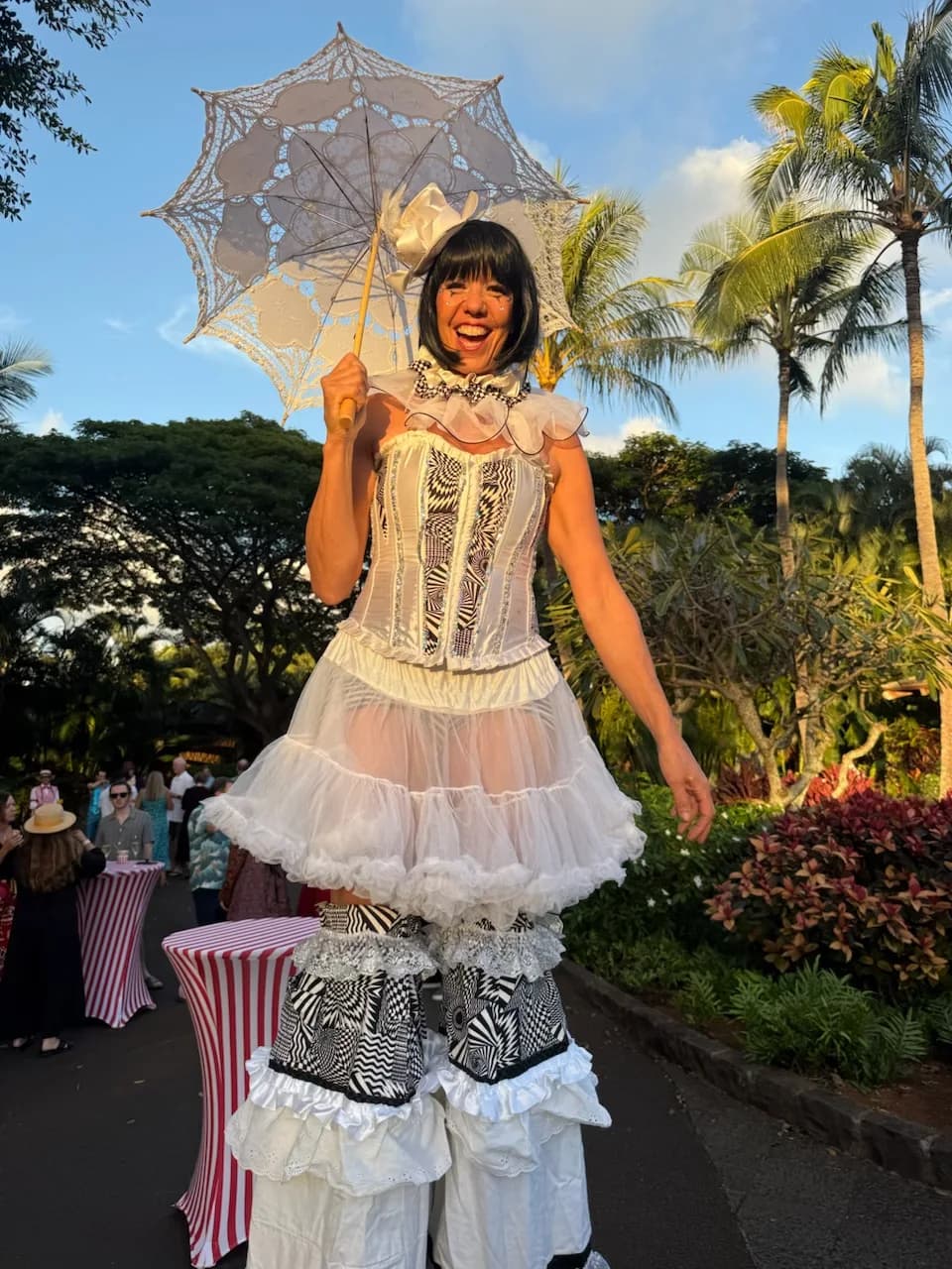 Stilt walker in white costume at an outdoor evening event